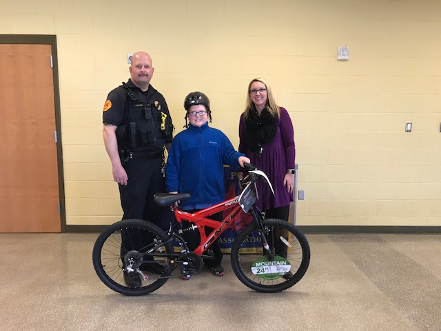Student who won bike standing by Officer Oliver and Mrs. Kammeyer.