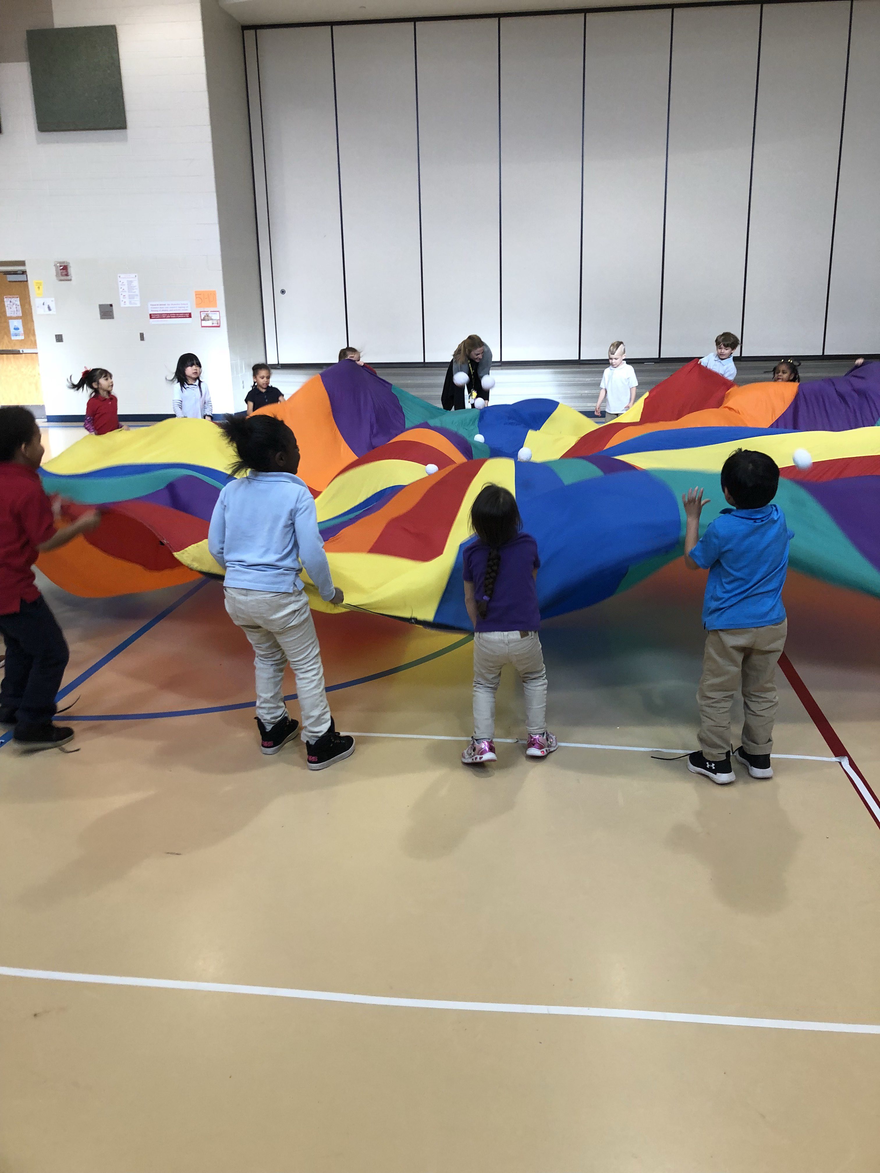 Kindergartners using a parachute in gym