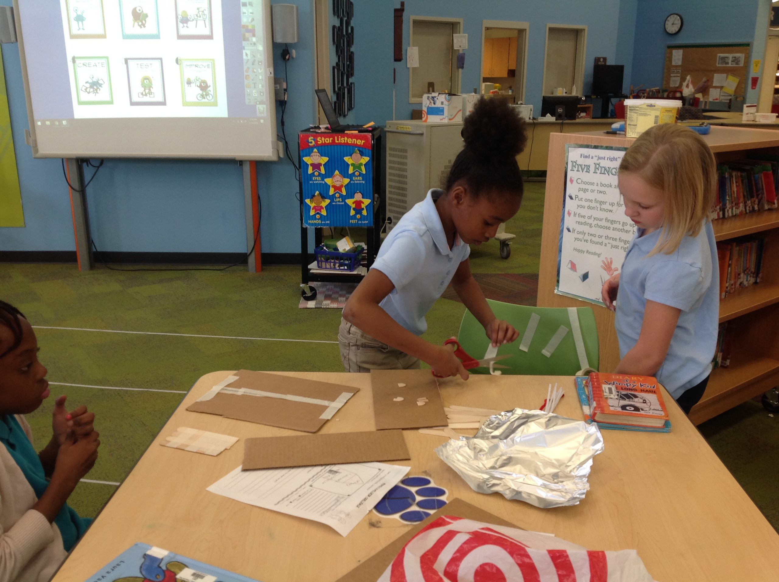 Two students cutting cardboard