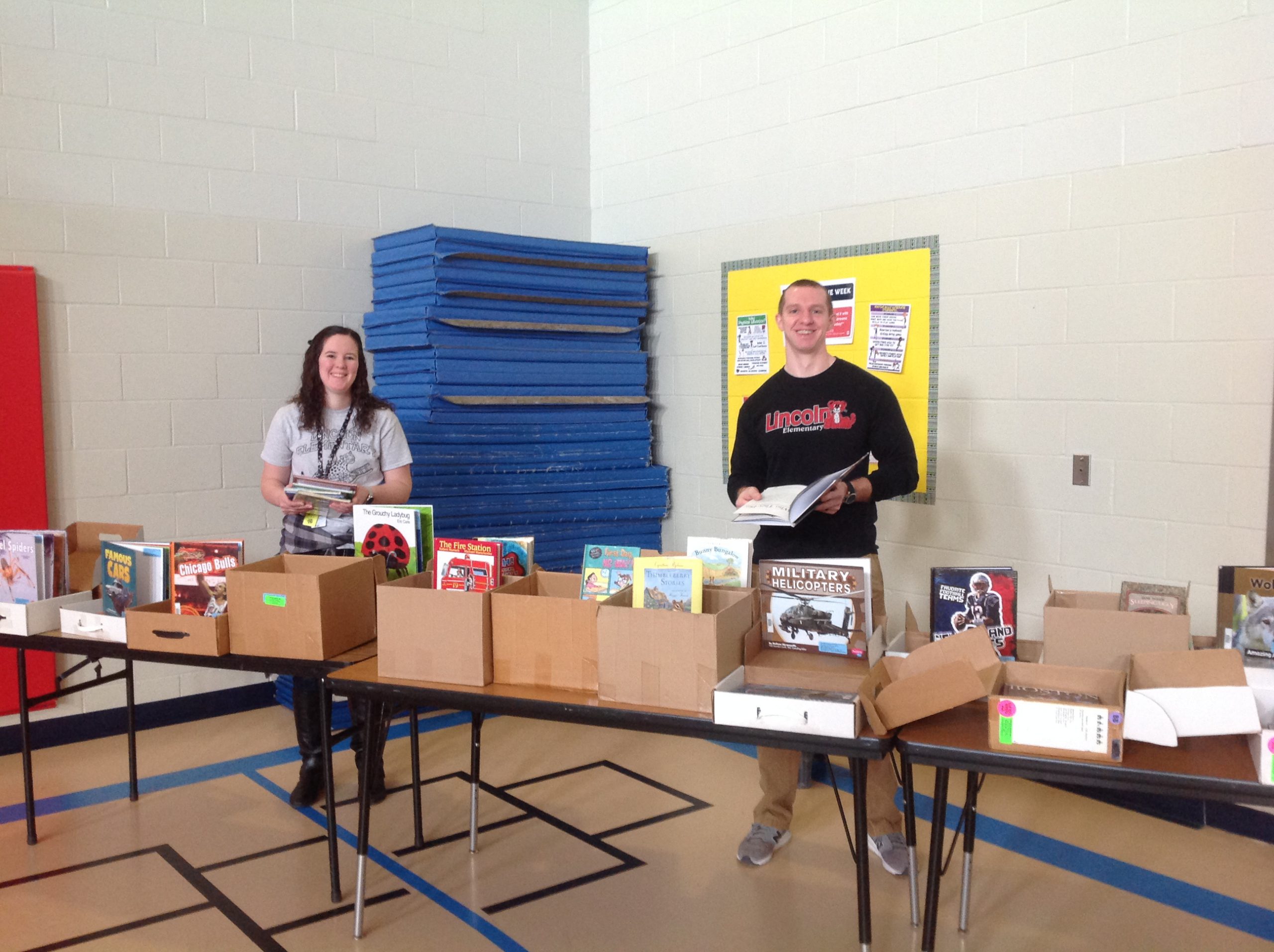 Two adults handing out books