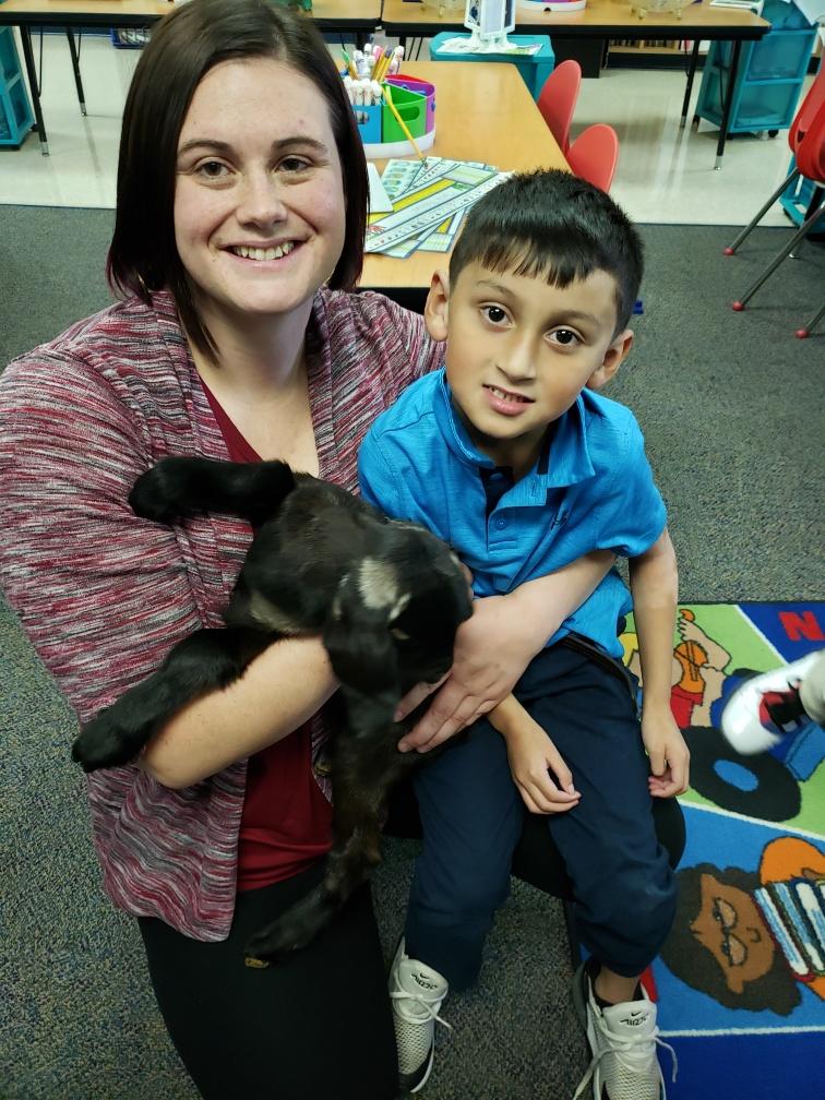 Child and adult holding a goat