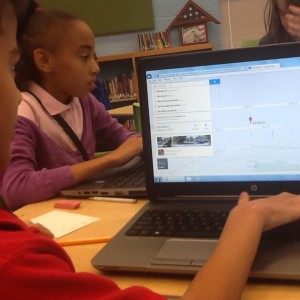 Three students looking at computers. One computer is on  Google Maps