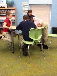 Four elementary students looking at an atlas