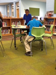 Two fourth grade students at a table looking at an atlas