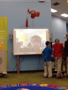 Three students talking into a computer to a girl online