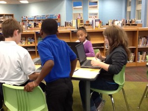 Four students at a table looking at their computers