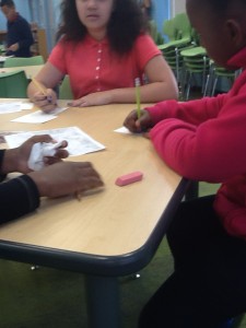 Three students writing down questions on paper