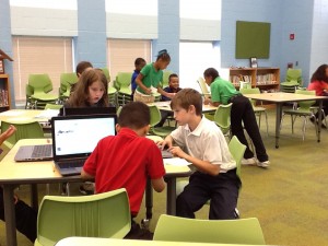 Group of 3 students looking at computers to research answers