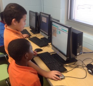 Two students working together at one computer solving coding puzzles