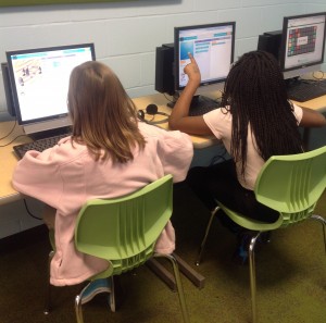 Two girls pointing at their computers learning how to computer code