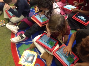 Four kindergarten students looking at their red iPads computer coding