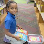 Child looking at a book during media check out