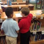two elementary Students looking for clues with their iPad
