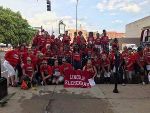 Lincoln Staff and Students smiling during parade with Lincoln Banner