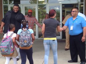 A family entering the school and high five greeters